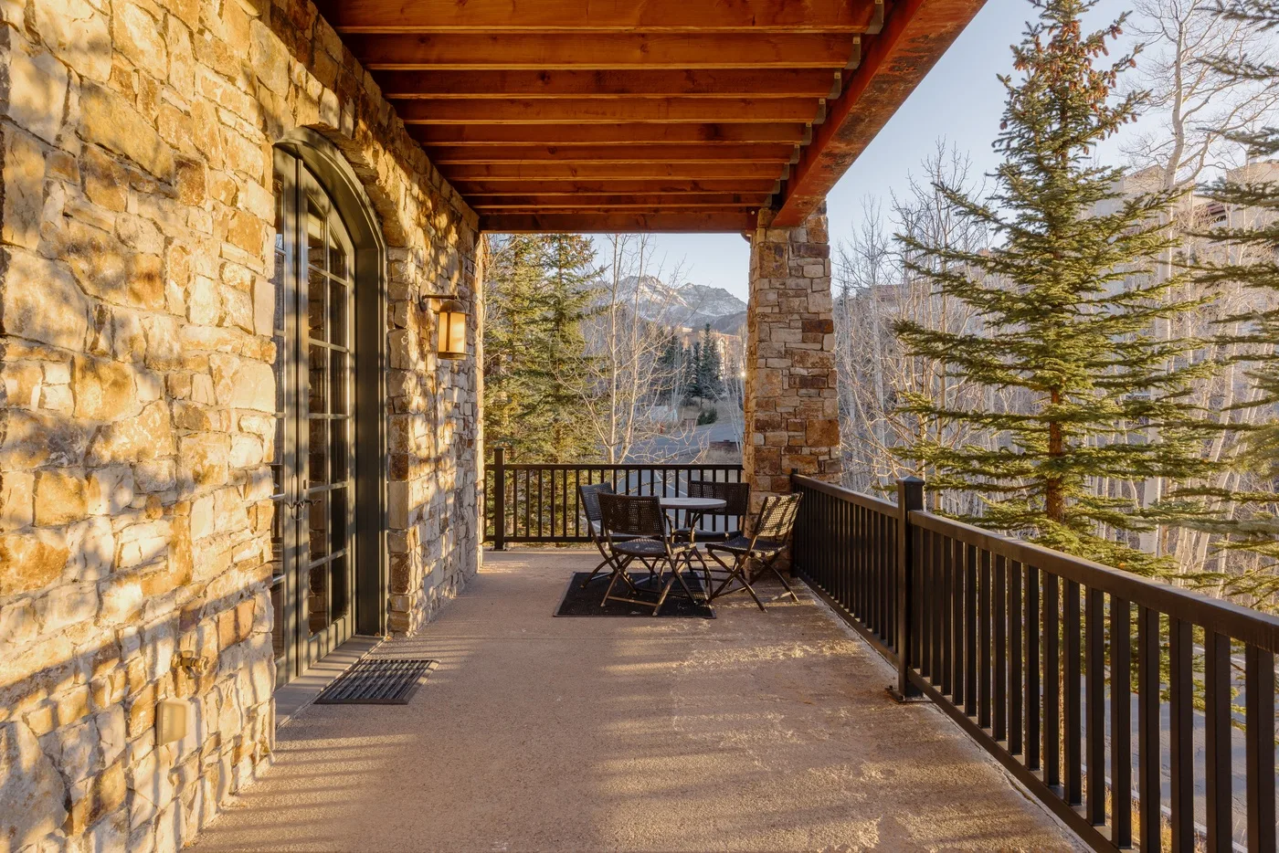 A covered outdoor terrace with seating overlooks trees and distant mountains.