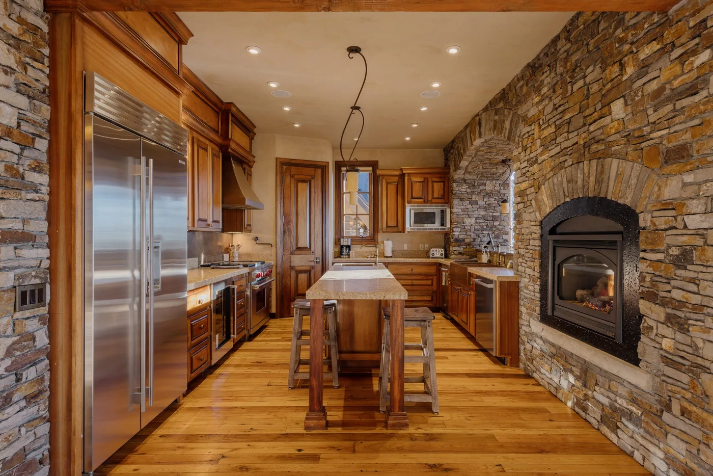 Una cocina rústica con gabinetes de madera, una isla central y una chimenea de piedra.