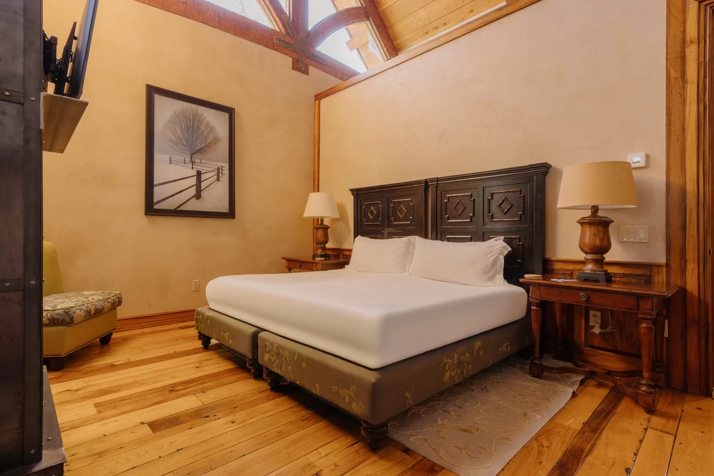 Un dormitorio con una cama grande, mesitas a juego y un techo de madera inclinado.