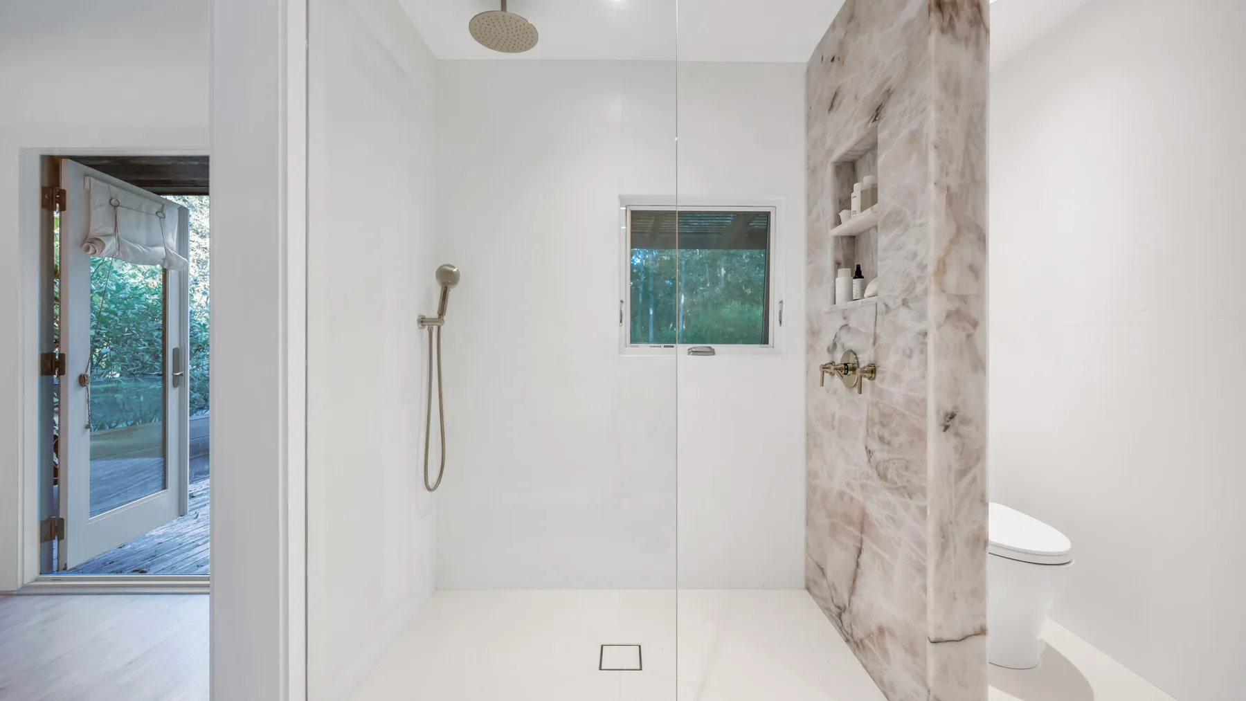 Un baño luminoso con ducha y una ventana.