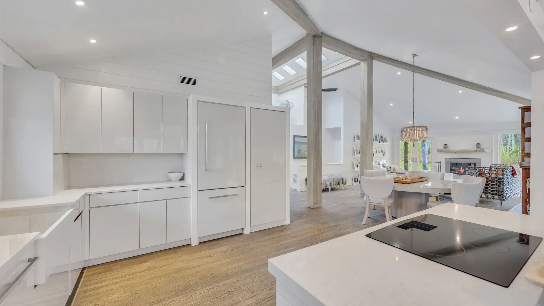 Una cocina y comedor diáfanos y luminosos, con muebles blancos y una mesa larga.
