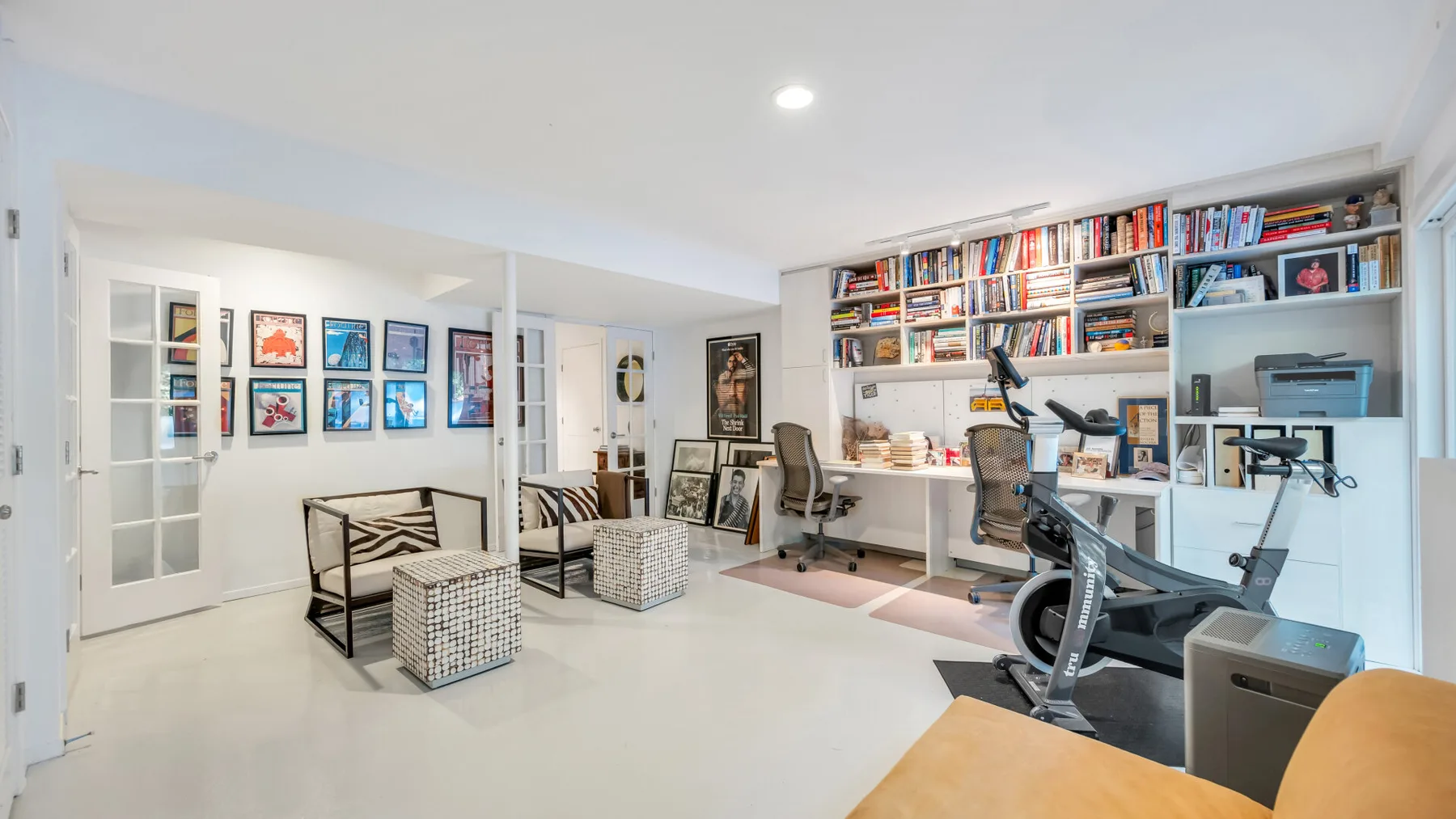 Un estudio luminoso con zona de estar, estanterías y asientos de escritorio.
