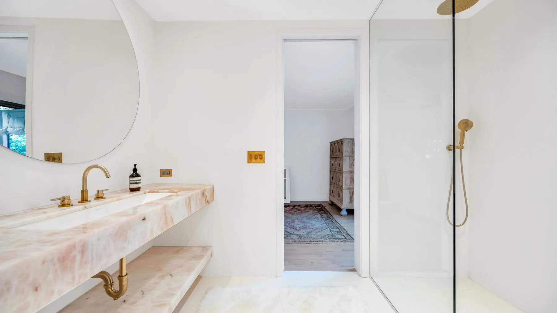 Un baño luminoso con un largo lavabo y una ducha de vidrio.