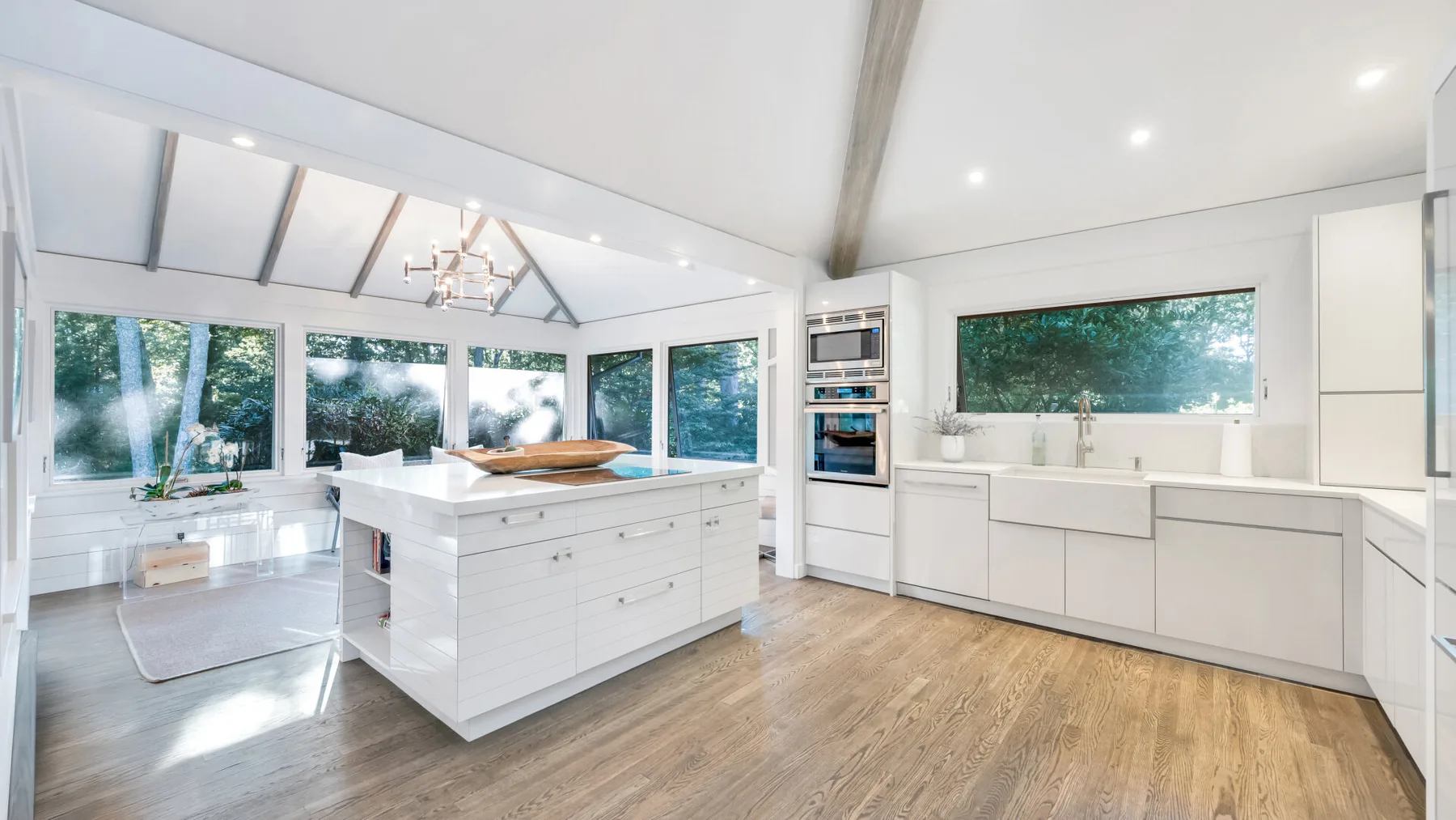 Una cocina luminosa con una gran isla y amplias ventanas con vistas a la vegetación.