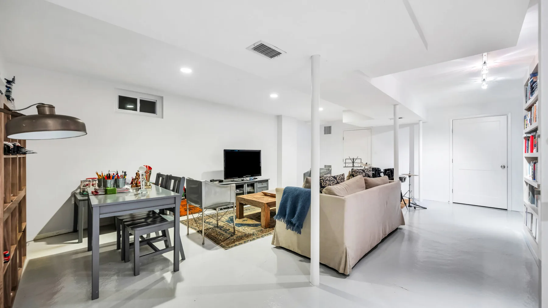 Una luminosa sala-comedor de planta abierta con asientos, una mesa y un televisor.