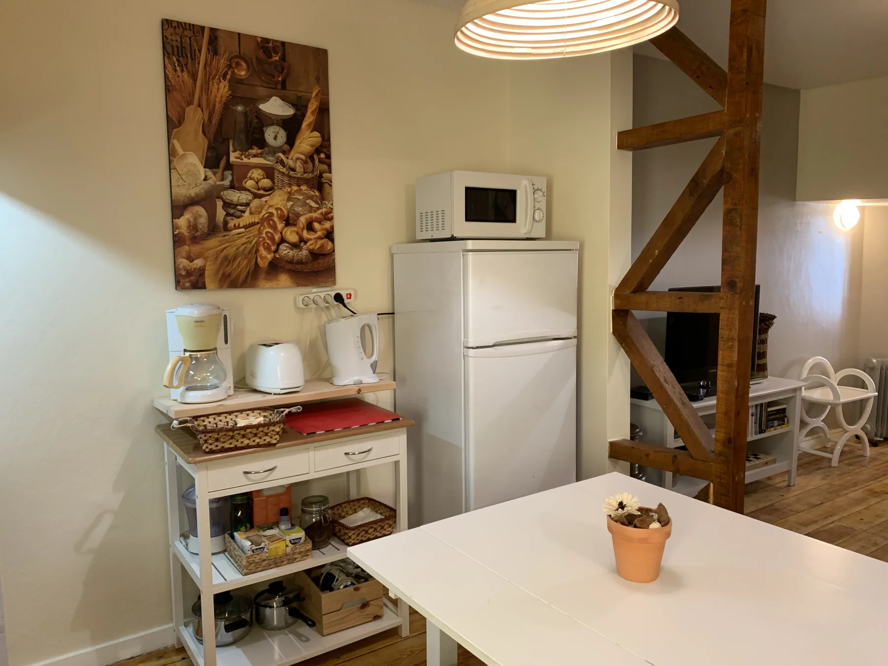 Una cocina compacta y zona de comedor con una mesa blanca y electrodomésticos.