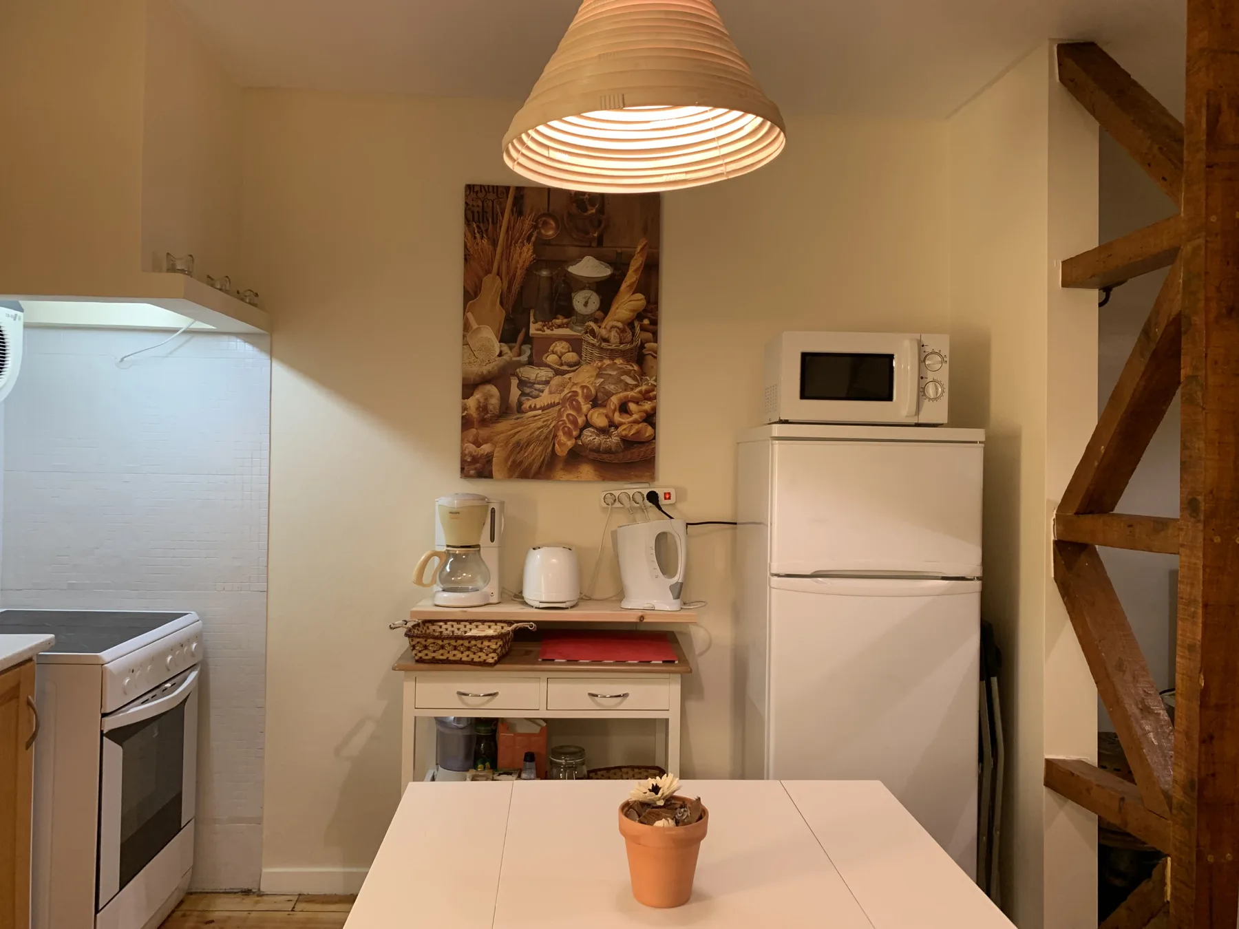 Una cocina compacta con refrigerador, pequeños electrodomésticos y una mesa de comedor.