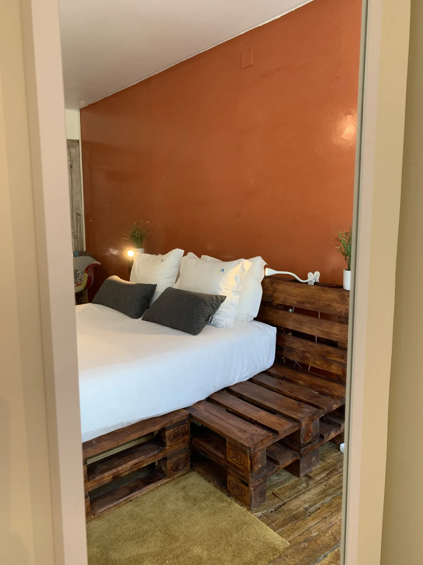 Un dormitorio con ropa de cama blanca y una estructura de cama de madera rústica.