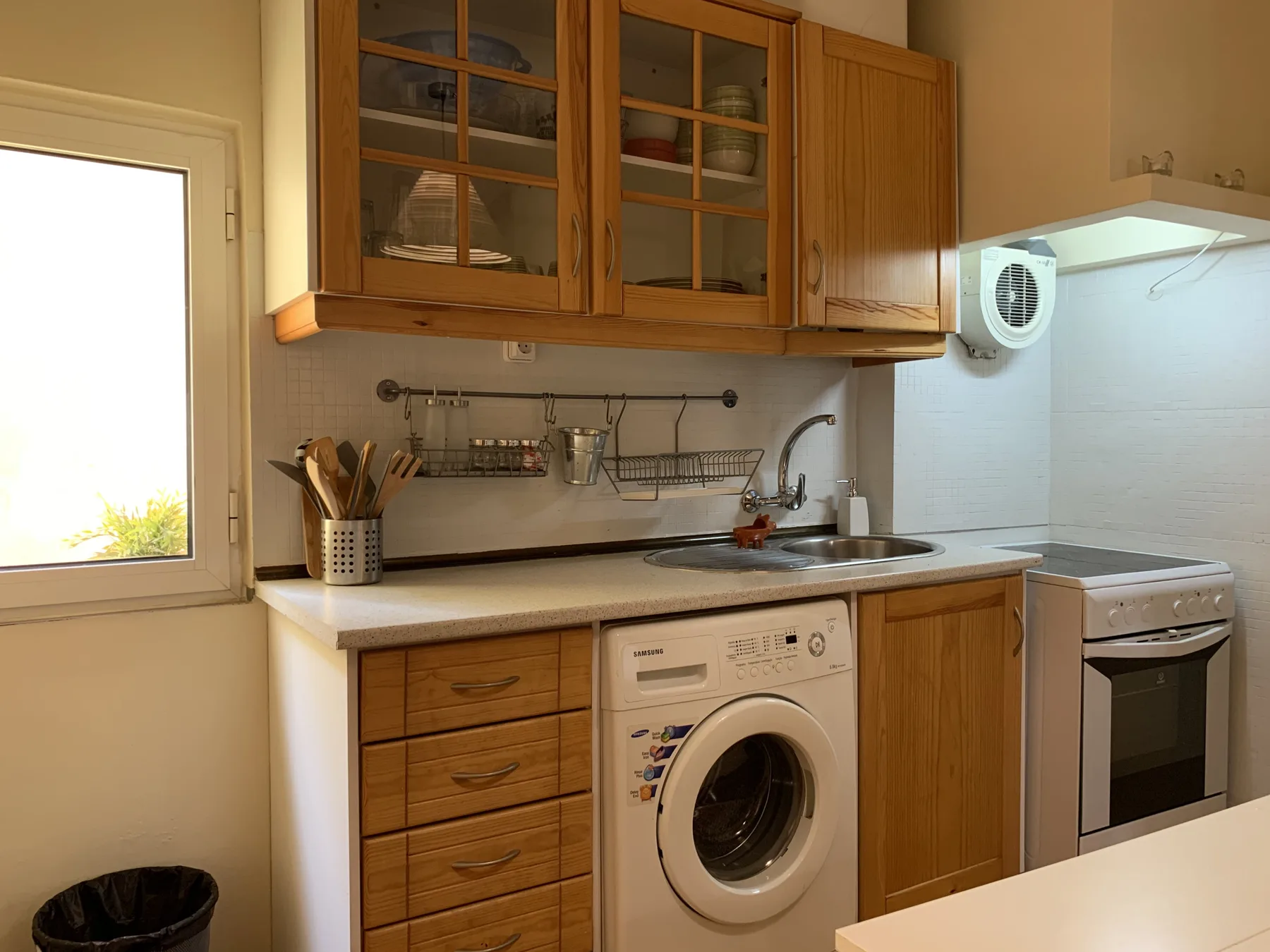 Una cocina compacta con armarios de madera y electrodomésticos junto a la encimera.