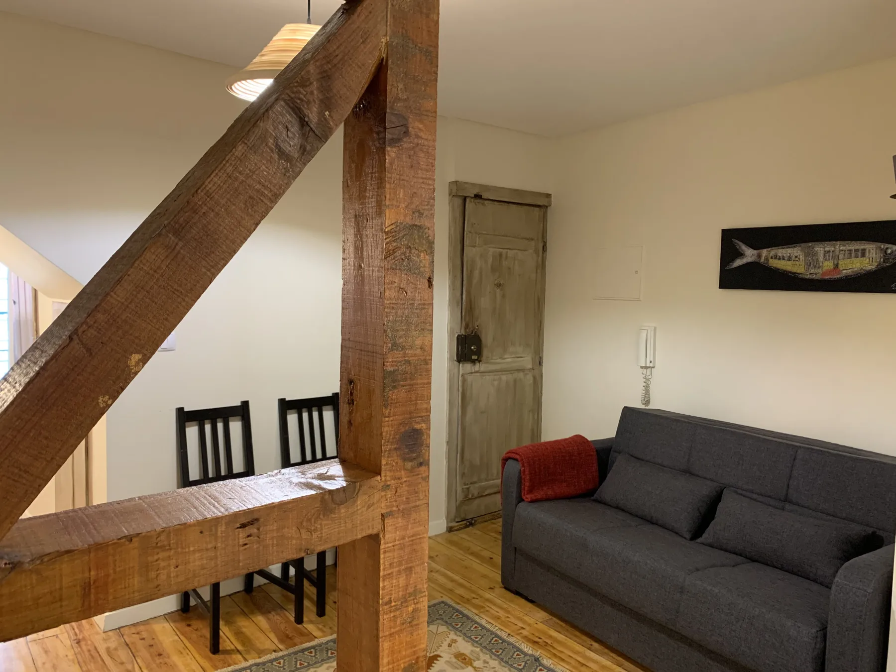 Sala de estar con un sofá gris y una mesa de comedor de madera.