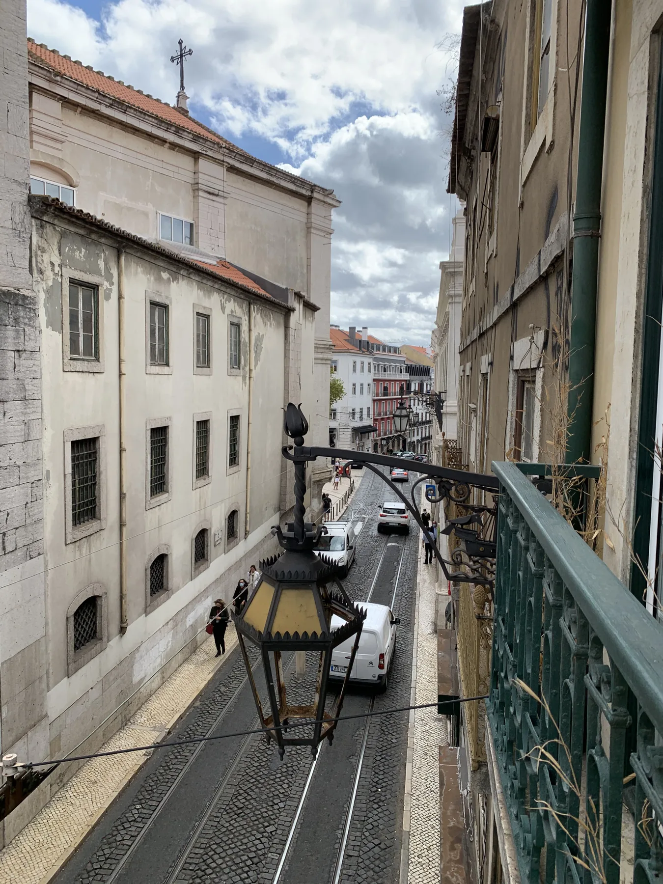 Una calle estrecha con adoquines, coches estacionados y edificios históricos.