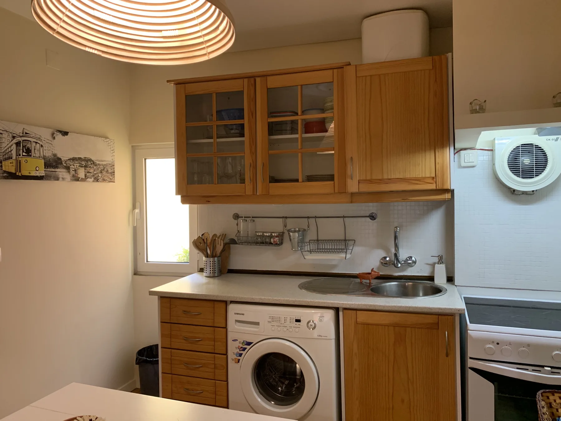 Una cocina compacta con armarios de madera, un fregadero y una lavadora.