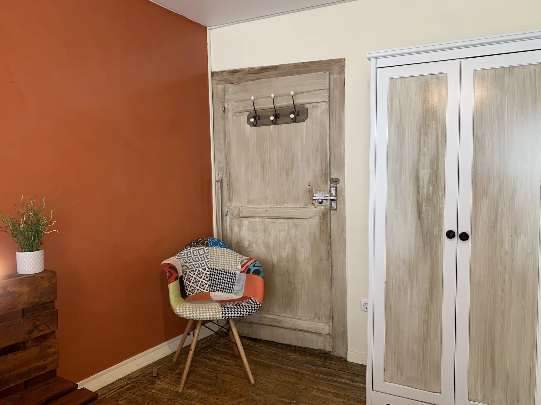 Un recibidor con una puerta de madera, perchas y una silla estampada.