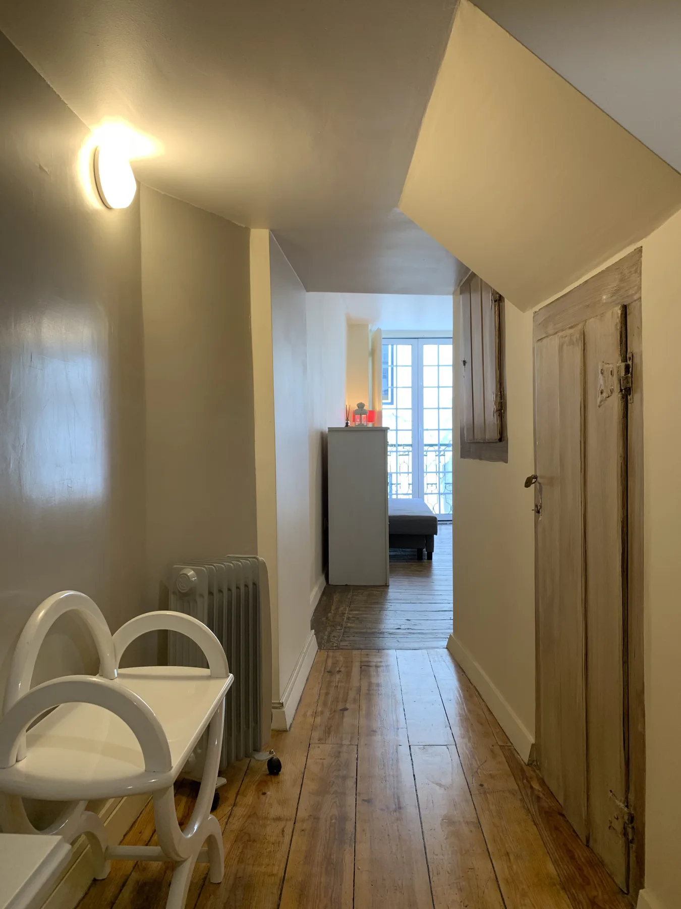 Un pasillo estrecho del apartamento conduce a una habitación luminosa, con sillas junto a la pared.