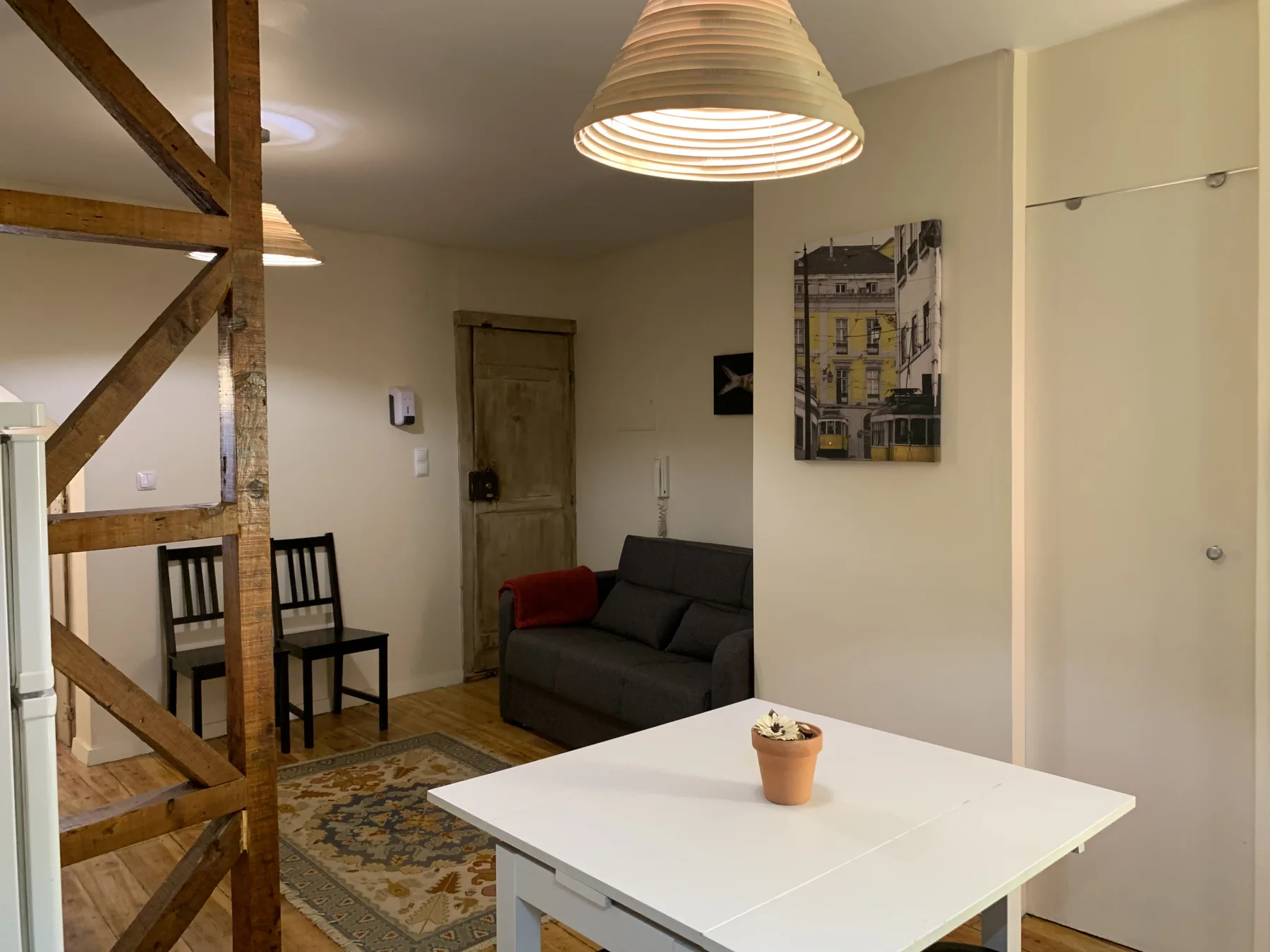 Una sala de estar con un sofá oscuro, una mesa blanca y un rincón de comedor.
