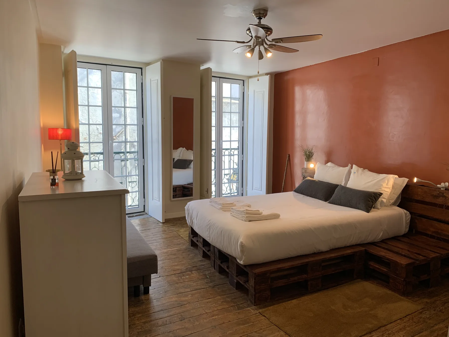Un dormitorio con una cama grande, lámparas de noche y ventanas altas.
