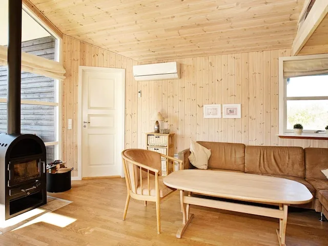 Una sala de estar revestida de madera con asientos alrededor de una mesa baja y una chimenea.