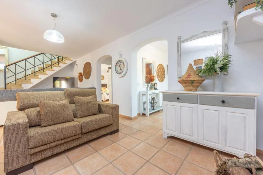 Una sala de estar con asientos marrones, suelo de baldosas y un mueble blanco.
