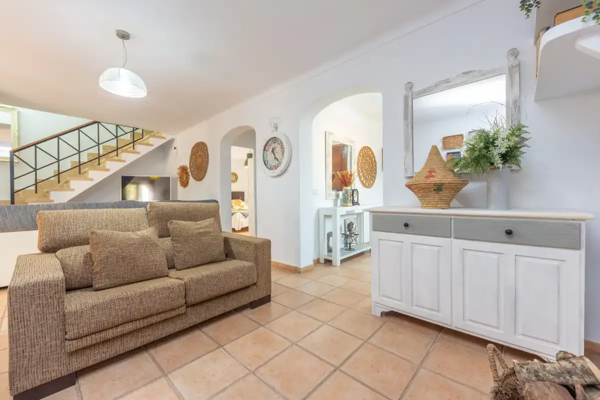 Una sala de estar con un sofá y una escalera al fondo.