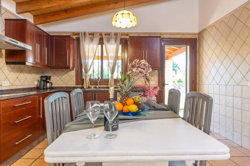 Una zona de comedor en la cocina con una mesa preparada con copas y fruta.