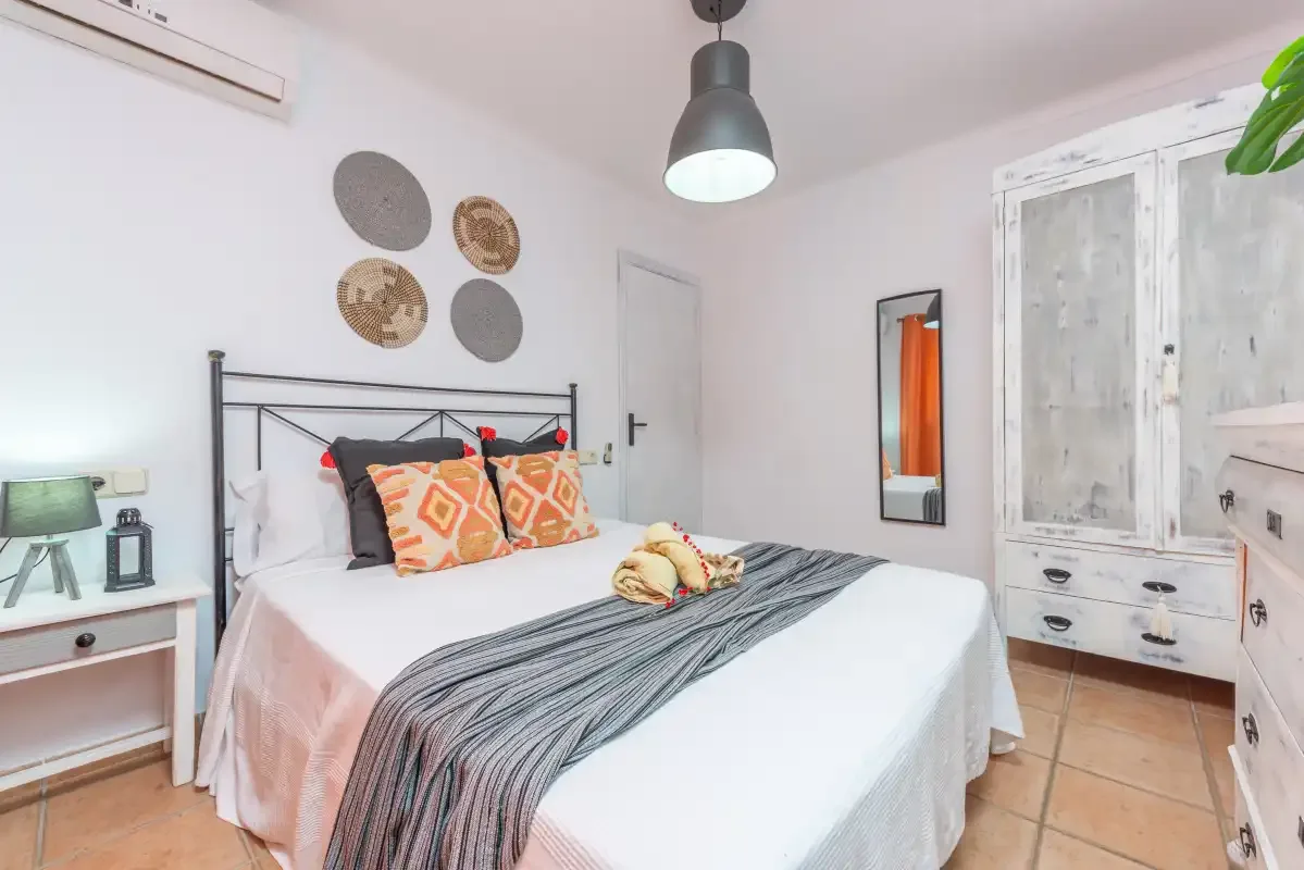 Un dormitorio con una cama bien hecha y un armario blanco.