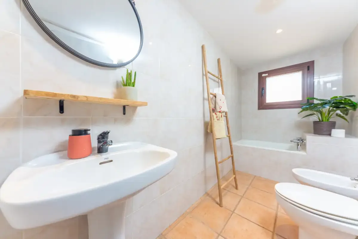 Un baño luminoso con lavabo, bañera y ventana.