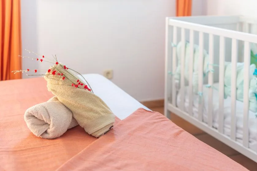 Un dormitorio con una cama y una cuna blanca al lado.