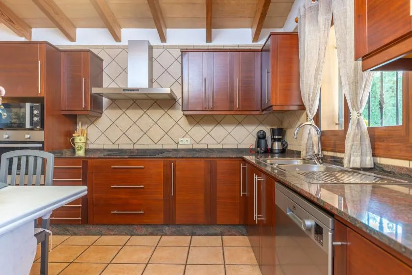 Una cocina con gabinetes de madera, un salpicadero de azulejos y una encimera larga.