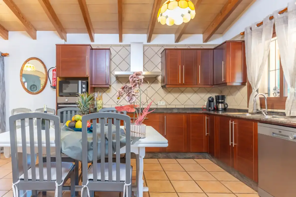 Cocina y comedor con armarios de madera y una mesa.