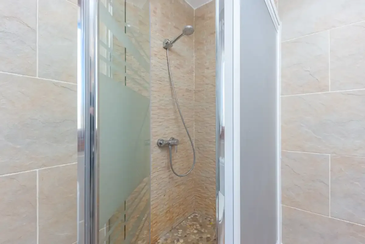Una ducha de baño con azulejos y un cabezal de ducha de mano.