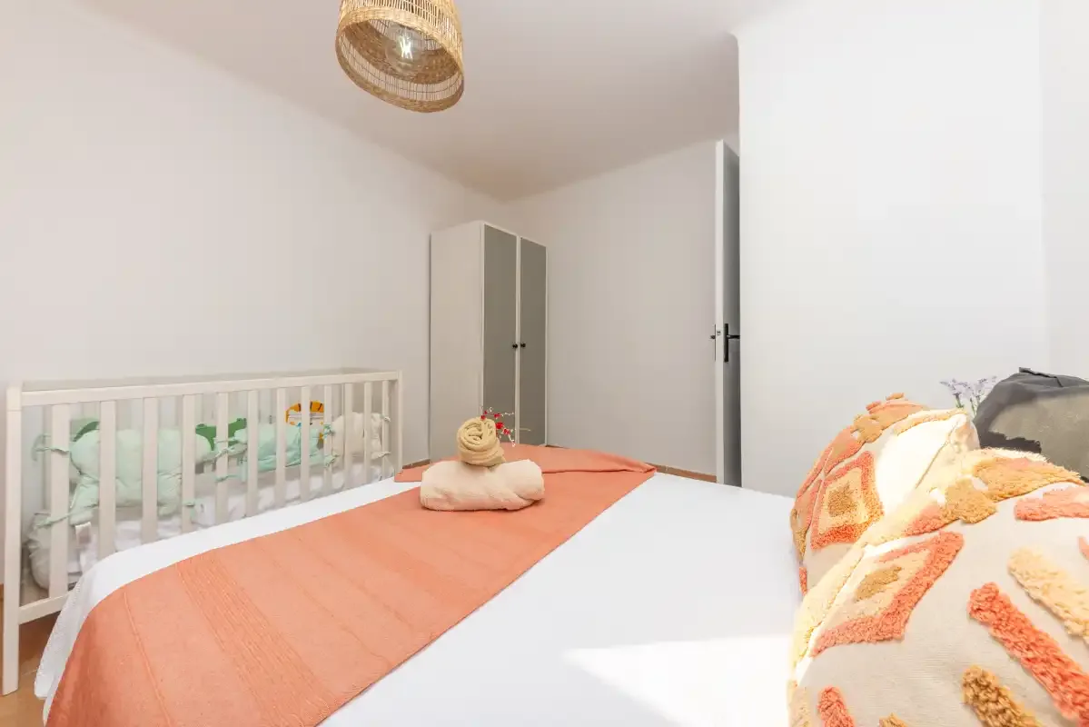 Un dormitorio con una cama, una cuna y un armario.