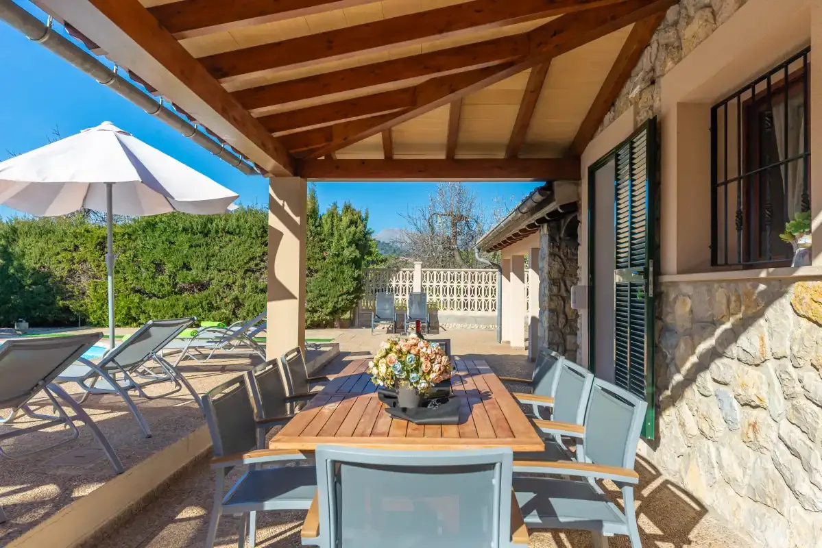 Comedor exterior cubierto con una mesa de madera y asientos de patio.