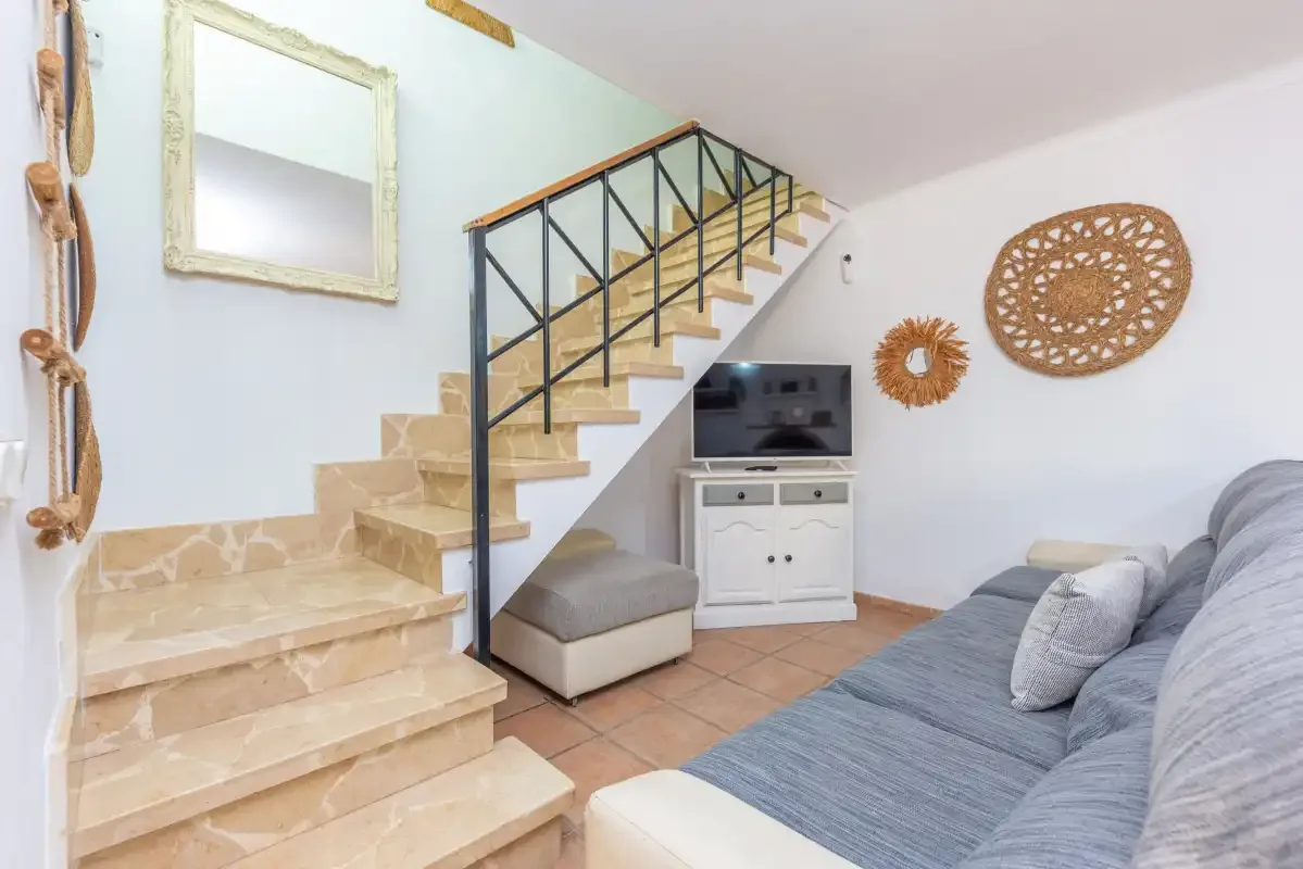 Una sala de estar con una escalera y un televisor junto a la zona de asientos.