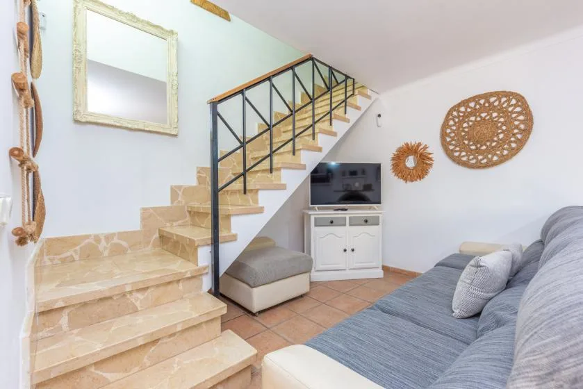 Una sala de estar con una escalera, un televisor y asientos.