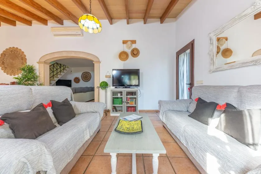 Una sala de estar con asientos frente a un televisor y una mesa de centro de vidrio.