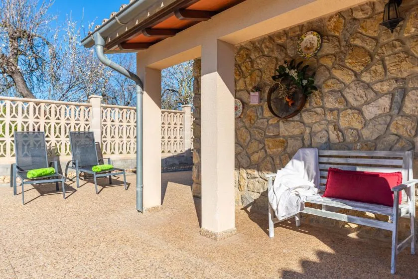 Un patio soleado con asientos al aire libre junto a una pared de piedra.