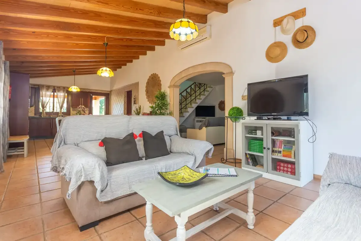 Una sala de estar con asientos, un televisor y una mesa de centro bajo vigas de madera a la vista.