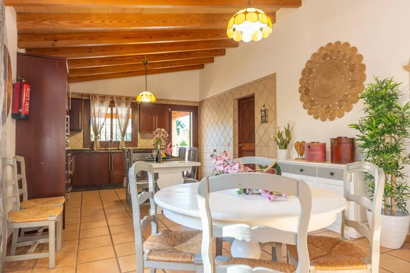 Comedor con una mesa redonda y sillas bajo vigas de madera expuestas.