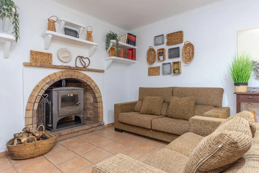 Una sala de estar con chimenea de ladrillo, sofá marrón y decoración de fibras tejidas.