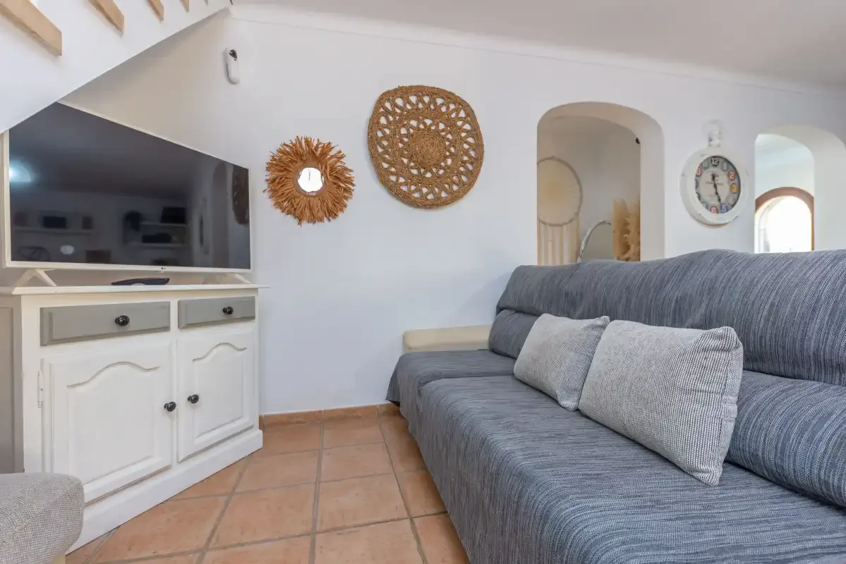 Sala de estar con asientos grises, un televisor y adornos en la pared.