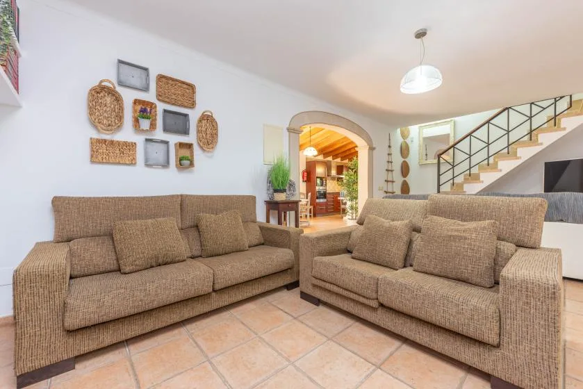 Una sala de estar con dos sofás marrones y una escalera al fondo.
