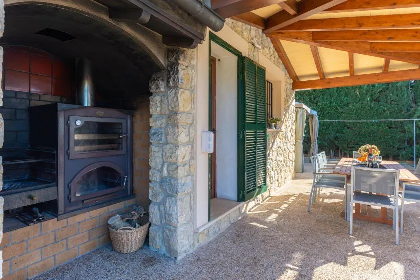Un patio cubierto de piedra con asientos al aire libre y un horno empotrado.