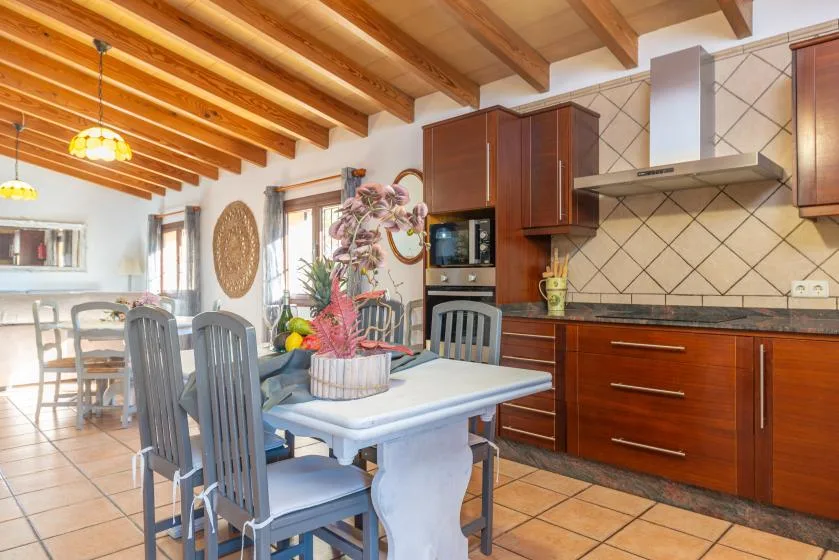 Comedor y cocina con gabinetes de madera y una mesa.