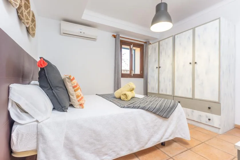 Un dormitorio luminoso con cama, armarios empotrados y una ventana.