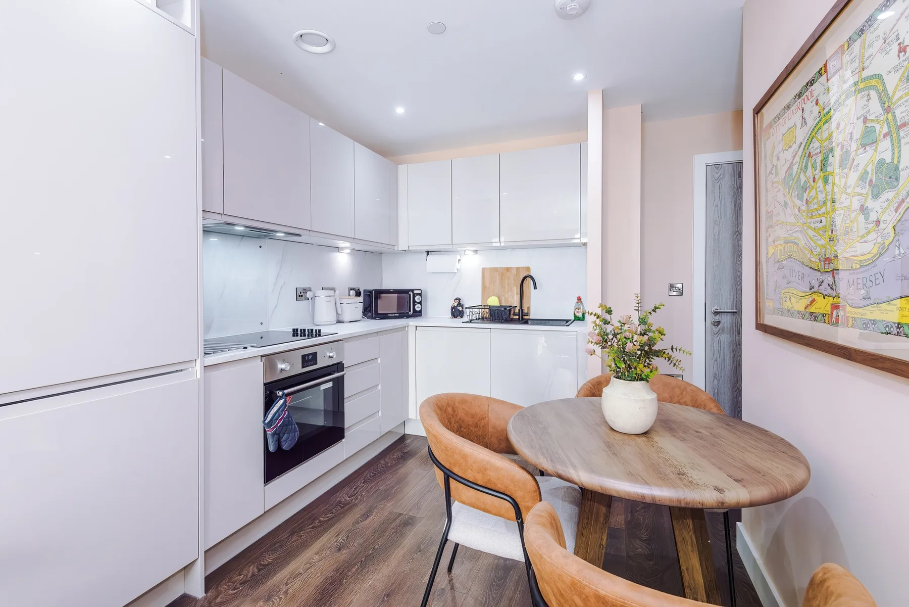 Una cocina luminosa con gabinetes blancos y una mesa de madera.