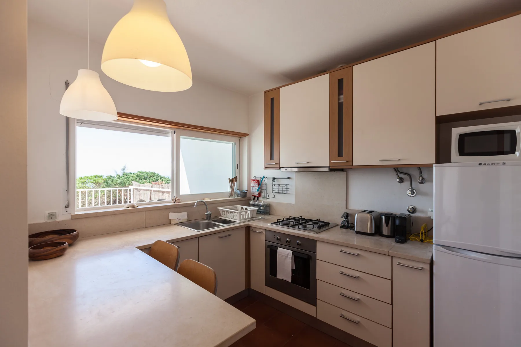 Una cocina luminosa con una ventana amplia sobre el fregadero y la encimera.