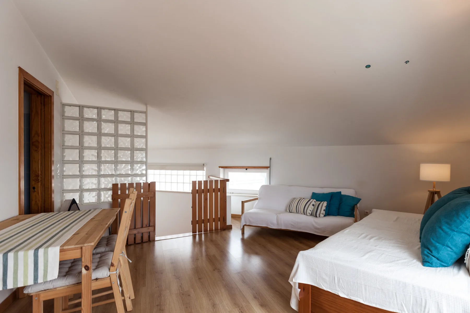 Una sala luminosa con asientos, una mesa de comedor y ventanas amplias.