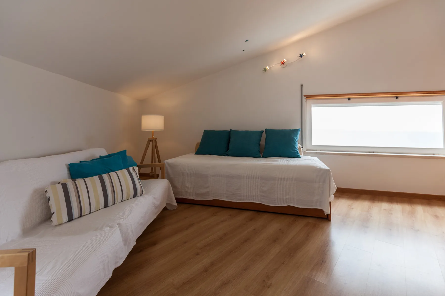 Un dormitorio luminoso con dos camas y una ventana amplia.
