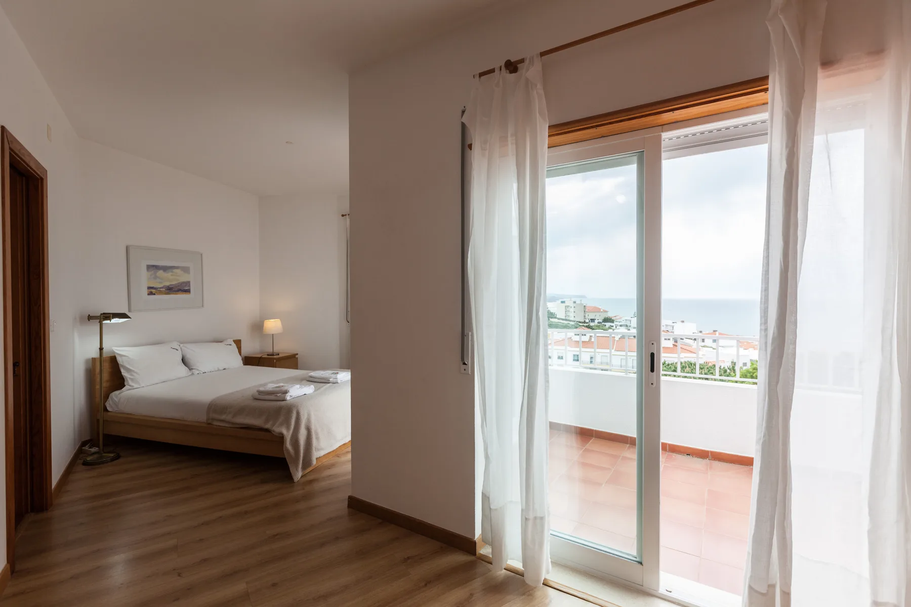 Un dormitorio con una cama junto a una puerta corrediza de vidrio que da a un balcón.