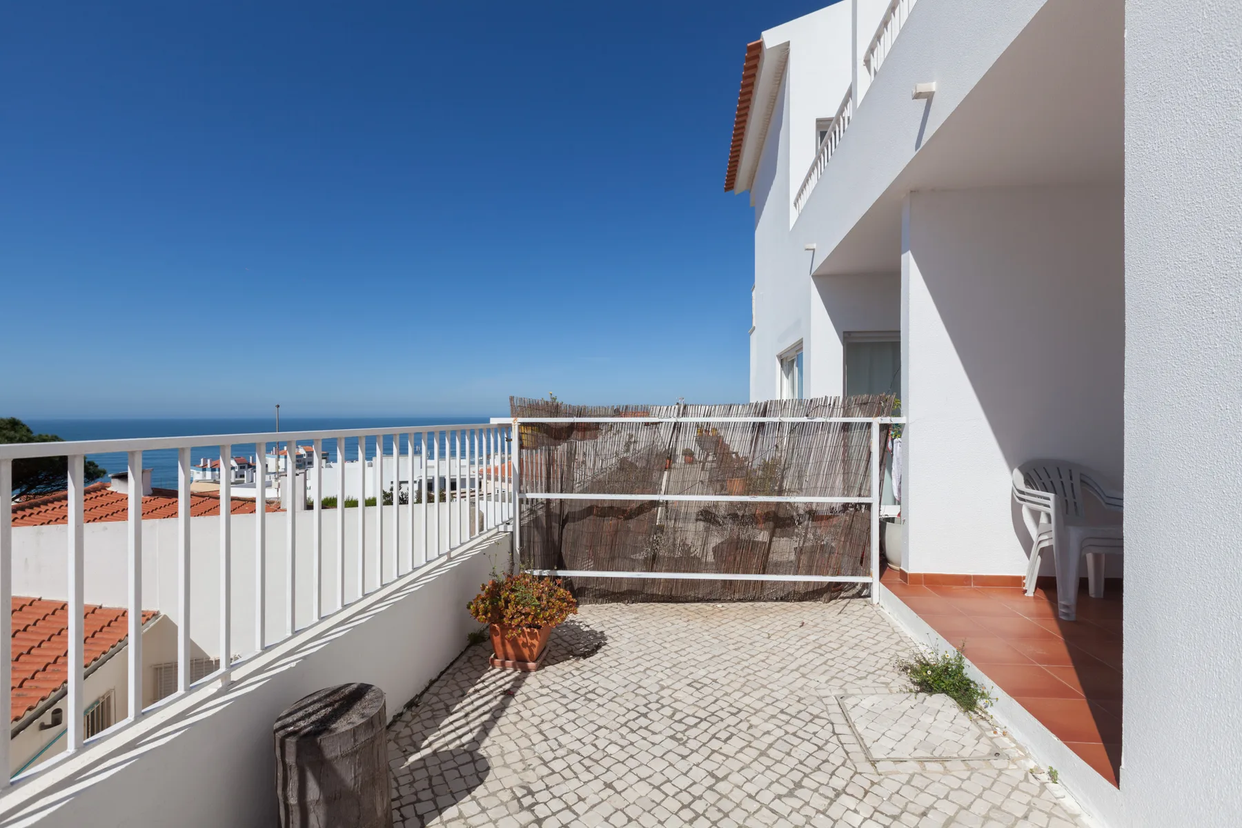 Una terraza soleada con suelo empedrado y vistas al mar.